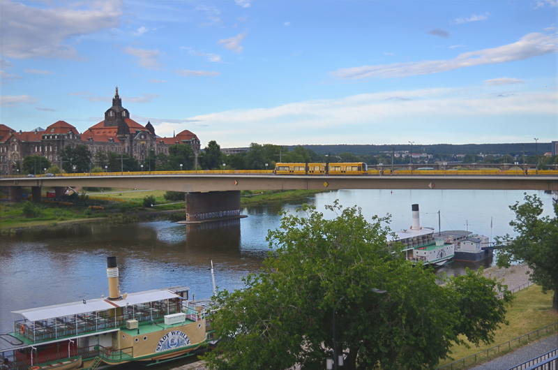 3 - A view from Brühl's Terrace in Dresden, Germany, looking toward the Carola Bridge as a yellow tram crosses the Elbe River past traditional paddle steamers